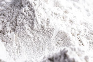 Kaolin siyah izole edilmiş, tozlu arka planda. Kaolin bir inorganik anayasa mineralidir, kimyasal olarak hareketsizdir, mevduatlardan çıkarılır ve farklı granülometrik bantlarda işlenir. Gıda endüstrisinde, kağıt ve mürekkepte kullanılır.