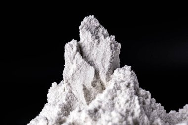 Kaolin siyah izole edilmiş, tozlu arka planda. Kaolin bir inorganik anayasa mineralidir, kimyasal olarak hareketsizdir, mevduatlardan çıkarılır ve farklı granülometrik bantlarda işlenir. Gıda endüstrisinde, kağıt ve mürekkepte kullanılır.