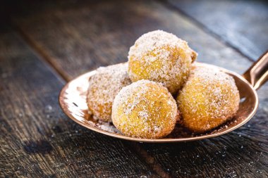 Fritule, kızarmış Hırvat usulü hamur tatlısı, sıcak servis ediliyor. Yuvarlak kaşık ve taze ev yapımı ekmek.