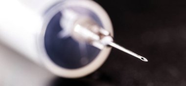 İzole edilmiş siyah zemin üzerinde şırınga ya da enjeksiyon, iğnenin ucunda nokta odaklı