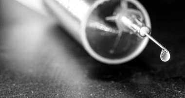 Tıbbi şırınga, iğneye odaklanma, düşen damla, damlayan sıvı, makro fotoğrafçılık, nokta odaklanma. Enjekte edilebilir uyuşturucu veya hastalık konsepti