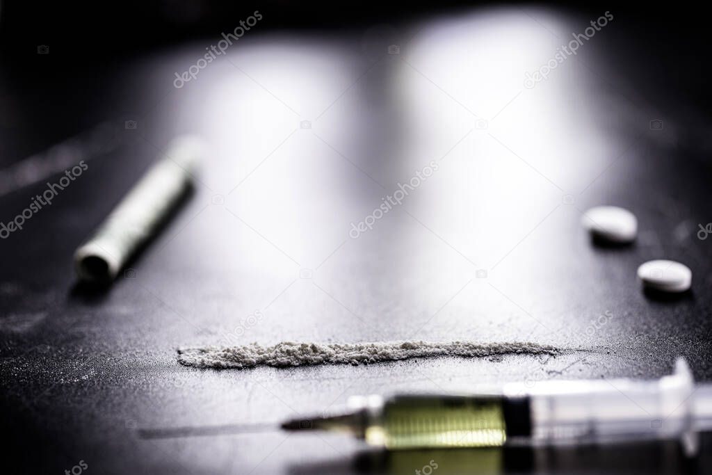 dope, narcotics, illegal drugs on dark black background. Heroin syringe, pills, cocaine.