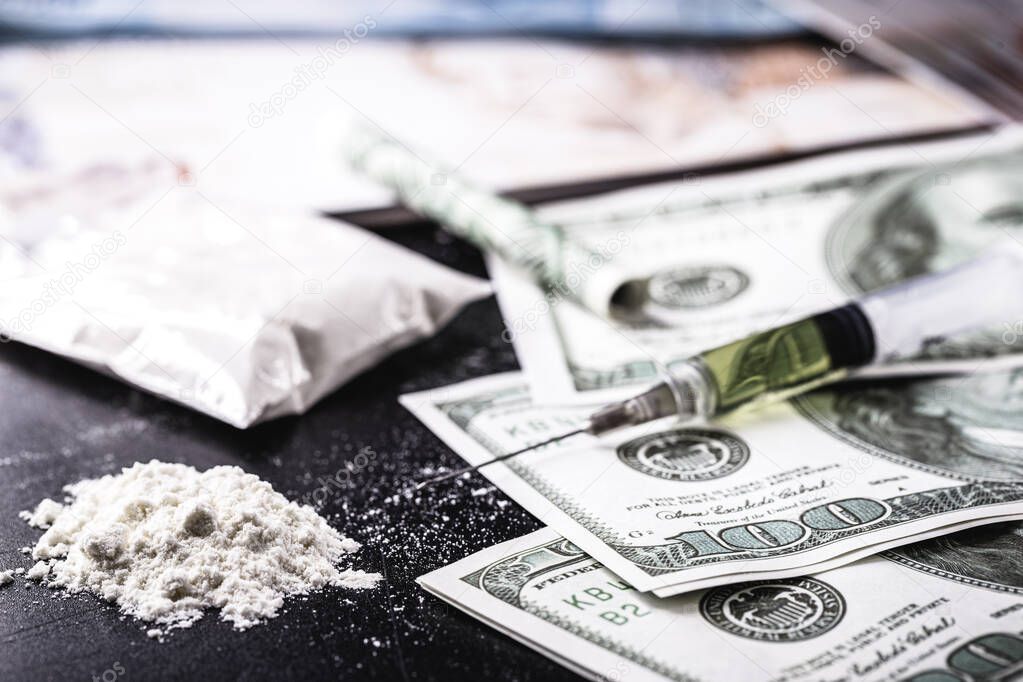 100 dollar bills and syringe with white powder, heroin and cocaine and money. Concept of drug dealers, international sale of drugs