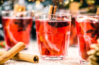 Baharatlı kırmızı şarap ve Noel meyveleri kırsal bir ahşap masada Noel renkleriyle ve ışıklarıyla. Geleneksel sıcak içecek Noel zamanı