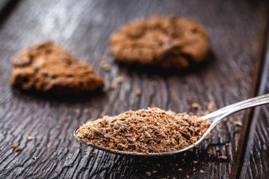 Çikolatalı kaşık, şekerlerde kullanılan çikolata tozu. Arka planda ev yapımı çikolatalı kurabiyeler var.