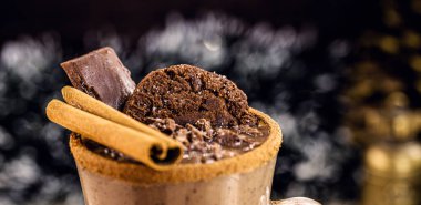 Noel temalı bir fincan sıcak çikolata, bayram için tipik bir içki. Tarçın üzerine odaklan, arkaplan ve noel süslemesi