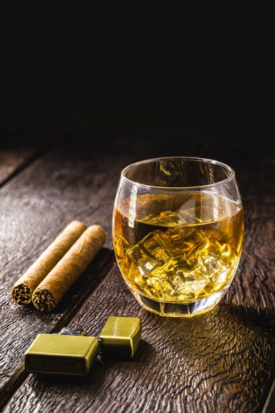 glass of whiskey with ice and cigar, strong drink, concept of relaxing moment, smoking