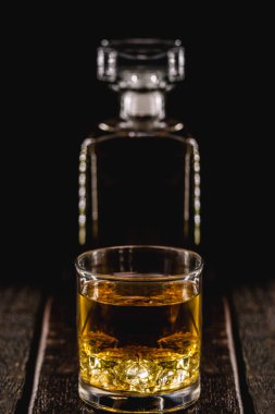 Damıtılmış içki, mat, sarı ya da altın rengi. Arka planda buz ve cam şişe, viski, burbon veya konyak.
