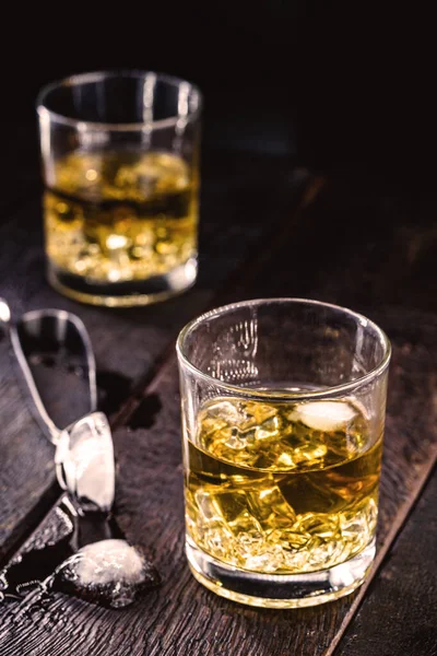 whiskey or bourbon, distilled drink with malt in glass with ice cubes, on isolated black background.