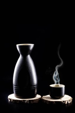Japonya 'dan gelen geleneksel damıtılmış ve fermente edilmiş alkollü bir içecek olan sake sıcak servis edilir, pirinç, su ve kojiden üretilir. Kopyalama alanı olan siyah arkaplan