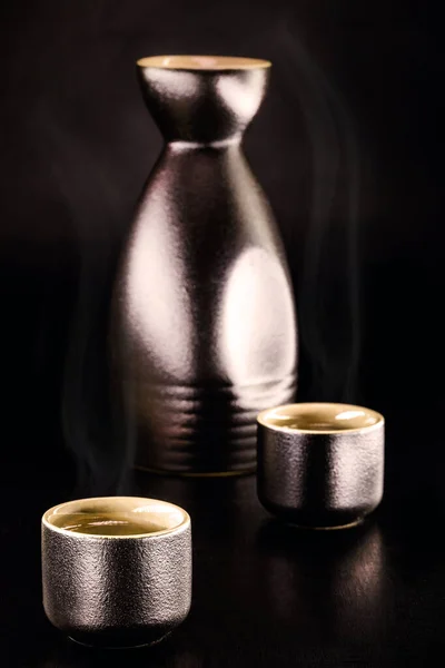 日本の伝統的な蒸留酒と発酵アルコール飲料である日本酒は 麹から作られた熱いものを提供した 黒の背景 — ストック写真