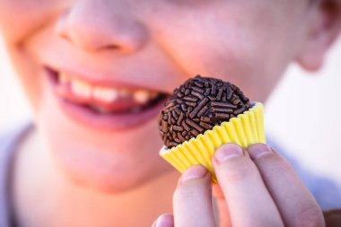 Brezilya çikolatası yiyen çocuk, granüle çikolatalı bonbon Brigadeiro deniyor.