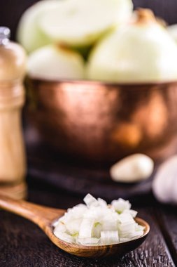 Arkasında sarımsaklı karanfil olan doğranmış organik soğanlı ahşap kaşık. Eski kırsal mutfak.