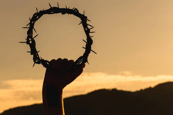 hand holding crown of christ on blue sky with clouds, hand of christ, easter concept ous exta passion fair