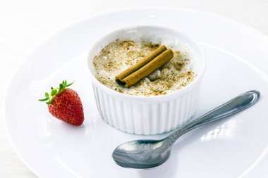 Beyaz bir kasede servis edilen tarçınlı ve çilekli kinoa lapası. Sütsüz, laktozsuz.