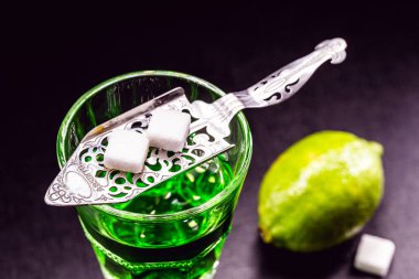 Koyu arkaplanda limon dilimleri ve beyaz şekerli absent.