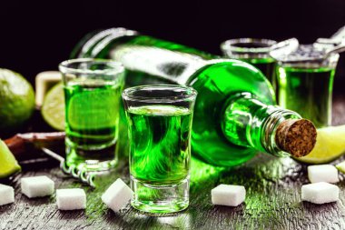 Bir doz absent ve küp şeker. Absinthe şişesi, yeşil damıtılmış içki.
