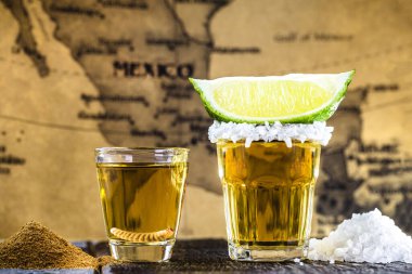 Tipik Meksika içecekleri, Mezcal tuzlu, biberli ve larvalı limon ve tuzlu tekila, arka planda Meksika haritalı.