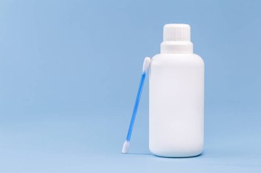 Beyaz plastik şişede hidrojen peroksit, pamuklu bez ve izole edilmiş mavi arka plan, ilaç konsepti, yaralar için ilaç ve küçük kesikler.