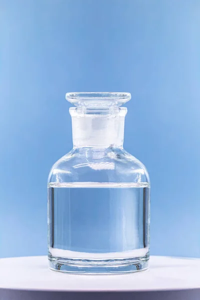 Reagent bottle with glass stopper, blue background, pharmacy or medicine concept, with copy space
