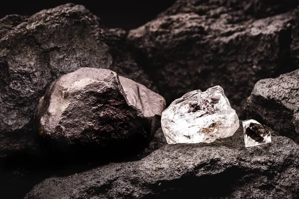 rough diamond next to a cut diamond, and coal stone in a coal mine.