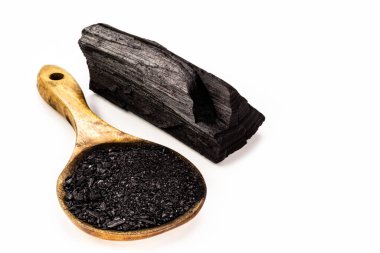 Etkinleştirilmiş kömür tozlu rustik ahşap kaşık, arka planda kömür parçaları, izole edilmiş beyaz arka plan