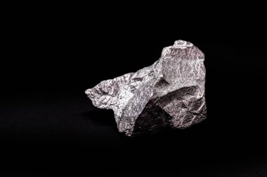 İzole edilmiş siyah zemin üzerinde ham çinko külçesi, alaşım ve çelik üretiminde kullanılan metal.