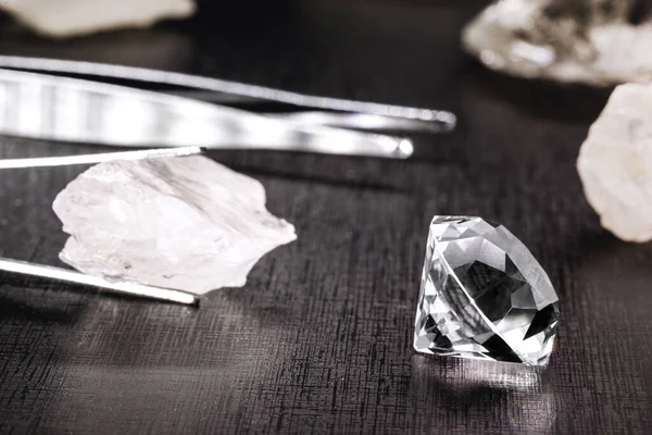 cut diamond with jeweler's tools and rough diamonds in the background, spot focus