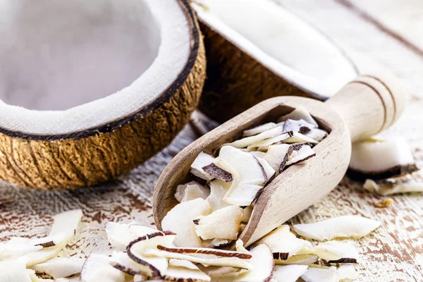 Wooden measuring spoon with coconut pieces and shavings, cooking ingredient.
