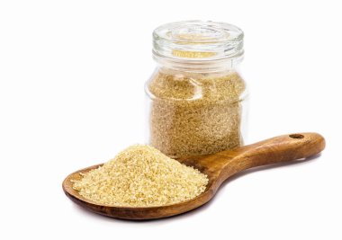 Rafine edilmemiş ham şeker yığınıyla ahşap kaşık ve arka planda boş alanla izole edilmiş cam kavanoz..