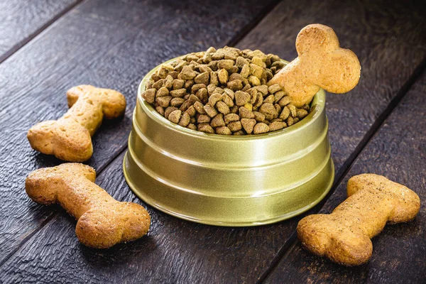 dog food with bone shaped dog biscuit in metallic bowl on wooden background, copy space