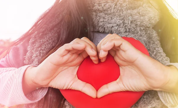 Vrouwen handen hart vorm gemaakt op rood hart — Stockfoto