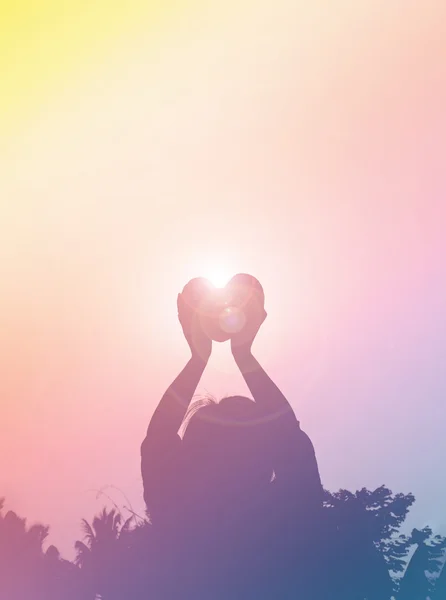 Silhouet achterkant van vrouwen verhogen haert naar hemel in schemering — Stockfoto