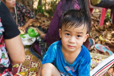 Ağaç gölge insanlar arasında altında oturan ve seyir sevimli Asya çocuk