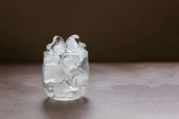 Forma de corazón agua de hielo liso en vidrio en la mesa con espacio de copia — Foto de Stock