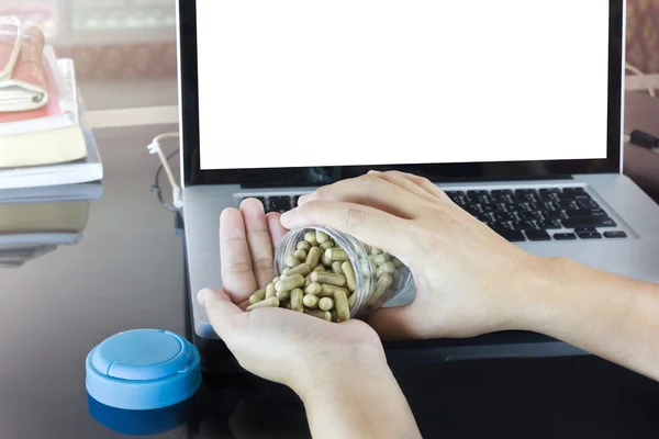 Hand and moringa capsules with blank screen notebook or computer — Stock Photo, Image