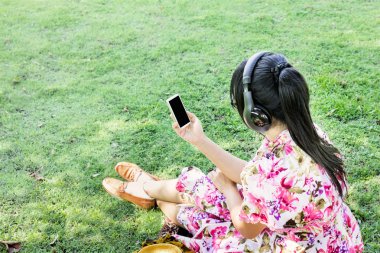 Genç Asyalı kadınlar geri veya görünümünde nadir kulaklık üzerinden müzik dinlemek