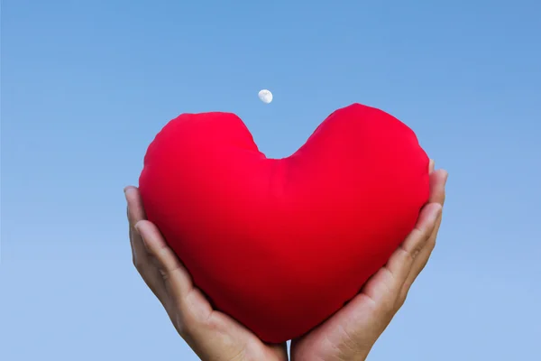 Geïsoleerde twee handen zachtjes verhogen en houd rood hart met liefde en respect met achtergrond van hemel — Stockfoto