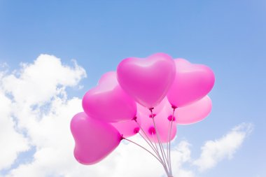 Group of lovely pink heart pattern balloons on blue sky clipart