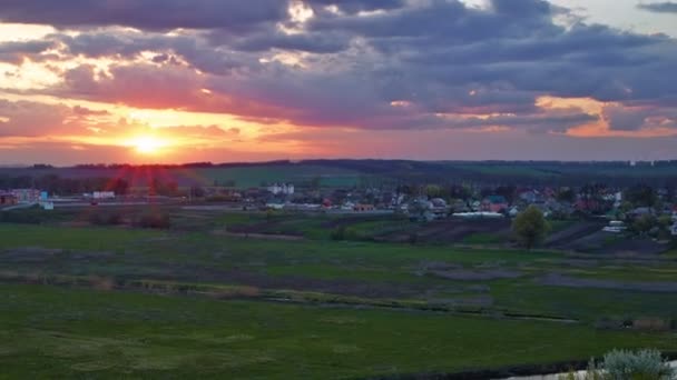 Vacker solnedgång över floden nära byn — Stockvideo