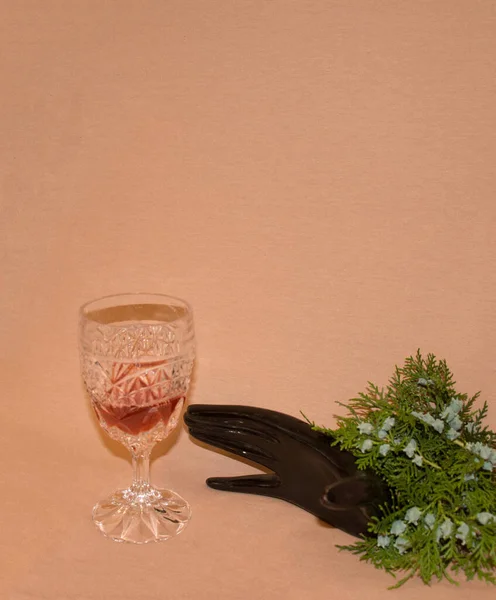 Can I have a glass of wine? A hand is stretched out of a pine tree to reach for the crystal glass. Celebration card. Minimalist concept.
