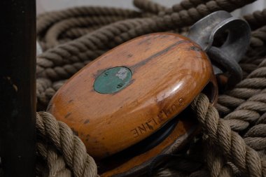A closeup of a traditional wooden block and ropes on a sailing ship. 