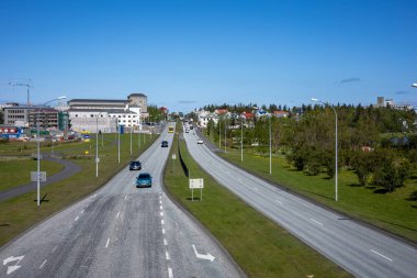 REYKJAVIK, ICELAND - 12 Haziran 2021: Njardargata üst geçidinden Hringbraut yoluna bir görüntü. Nadir araba trafiği ve sarı bir şehir otobüsü. 