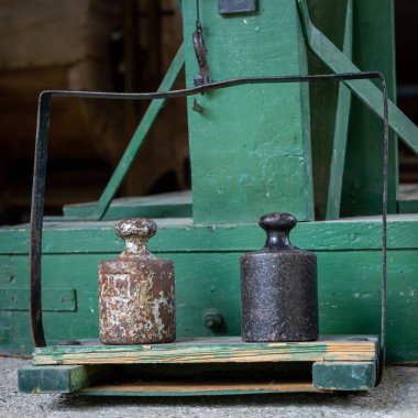 A closeup of a vintage, green weighting machine and two iron weights.  clipart