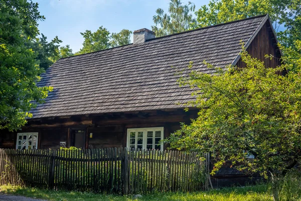 OPOLE, POLAND - June 20, 2021:A traditional wooden house with wooden fence, surrounded by trees, on sunny summer day, in an open-air museum The Opole Village. 