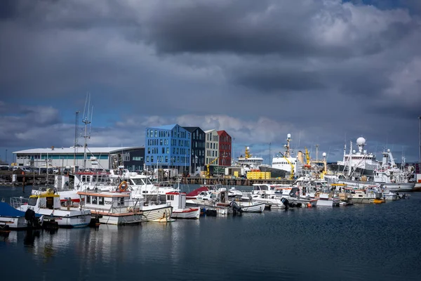 HAFNARFJORDUR, ICELAND - 16 Temmuz 2021: Hafnarfjordur balıkçı limanı - küçük tekneler ve renkli liman binaları. Gökyüzünde fırtınalı bulutlar. 