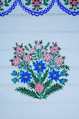 ZALİPİ, POLAND - 1 Ağustos 2021: Beyaz ahşap bir duvara boyanmış geleneksel, renkli bir çiçek deseni. 