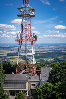 SLEZA, POLAND - 07 Ağustos 2021 Sleza Dağı 'nın tepesinde ağaçlarla çevrili radyo ve televizyon direği, Sudetes Foreland. Güneşli yaz günü, mavi gökyüzü. 
