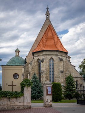 Stopnica, POLAND - 1 Ağustos 2021: Stopnica, Poland.Ön kapıdaki bir ortaçağ kilisesi. Bulutlu bir gün.