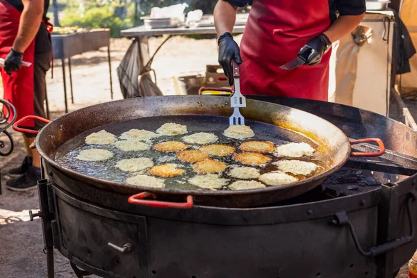 Chef fríe panqueques de papa en una sartén grande —  Fotos de Stock